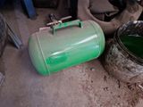 a green tank sitting on the ground next to a dirty toilet