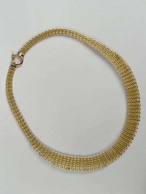 gros plan d'un collier en or sur une surface blanche