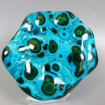 blue and green glass object with a white base on a white surface