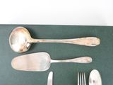 silverware on a green place mat with a spoon, fork, and knife rest