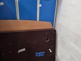 a chest in the corner of a room with two blue lockers