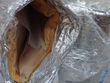 a sandwich wrapped in aluminum foil sitting on a table