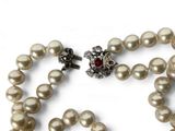 pearl necklace with a red stone and silver clasp on a white background
