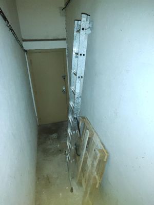 une échelle appuyée contre un mur dans une pièce étroite