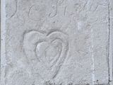 un parpaing sur lequel est gravé un cœur, posé sur un trottoir