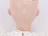an old doll with a white dress and lace on it