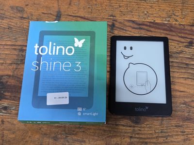 a kindle that is sitting next to a book on a table