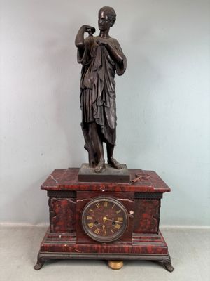 une statue de femme tenant une horloge sur une table