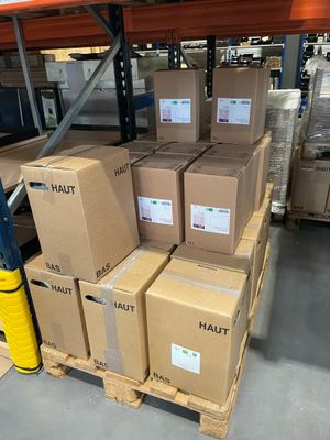 des cartons empilés sur des palettes dans un grand entrepôt, avec des palettes au premier plan