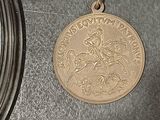 a silver clock and a gold medal on a table