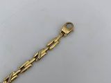a close up of a gold bracelet on a white surface