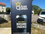 une pancarte sur laquelle est écrit « Just Queen » et une canette de bière