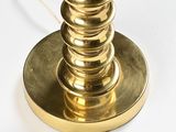a gold table lamp on a white table with a black background