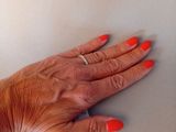 a woman ' s hand with red nails and a ring on it