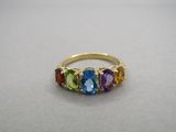 un gros plan d'une bague en or sertie de cinq pierres de couleurs différentes