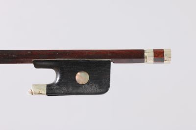 un gros plan d'un archet de violon posé sur une surface blanche
