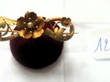 une broche en or ornée de fleurs, présentée dans un écrin en velours rouge