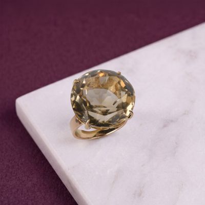une photo d'une bague sertie d'une topaze jaune posée sur une surface en marbre