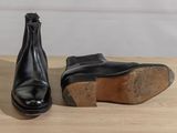 pair of black leather boots sitting on top of a wooden table