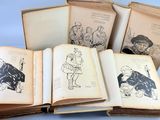 several old books with drawings on them sitting on top of a table