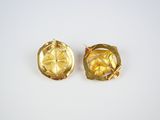 a pair of gold earrings on a white surface