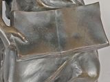 statue of a woman holding a book and a purse