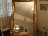 un grand miroir dans un coin de la pièce, à côté d'un fauteuil
