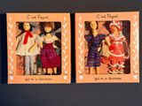 two boxes with dolls in them on a table