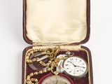 une petite boîte contenant une montre de poche et une chaîne en or