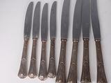 six knives are lined up in a row on a white surface