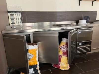 une cuisine équipée d'un plan de travail en inox et d'une poubelle