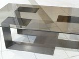 a glass table with a metal base on a tile floor