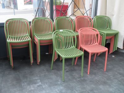 Plusieurs chaises vertes et rouges sont alignées devant une fenêtre