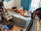 a messy room with a bed and clothes on the floor