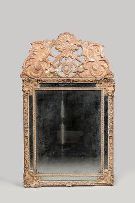 un miroir richement sculpté, doté d'un cadre doré sur fond gris