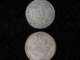 two silver coins sitting side by side on a black surface