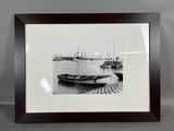 photographie en noir et blanc d'un bateau amarré à un quai, avec d'autres bateaux en arrière-plan