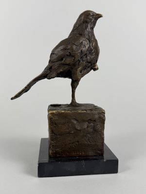 bronze sculpture of a bird on a rock on a white background