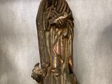 statue en bois représentant un homme barbu tenant un chien dans ses bras