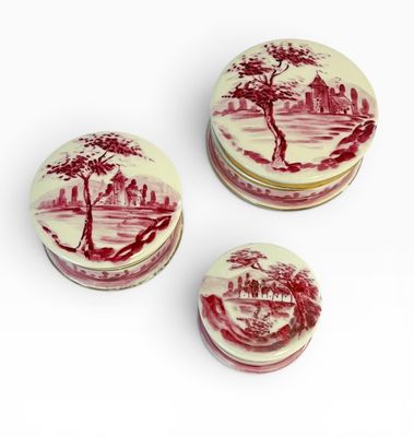 trois boîtes rouges et blanches ornées de motifs, posées sur une surface blanche