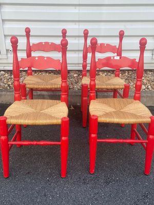 pair of red chairs with wicker seats in front of a white wall