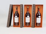 trois bouteilles de vin dans un coffret en bois sur une surface blanche