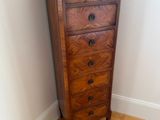 a tall wooden chest of drawers in the corner of a room