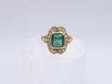 un gros plan d'une bague en or sertie d'une émeraude entourée de diamants