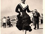 black and white photograph of a woman in a dress walking down a street