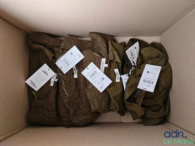une boîte en carton remplie de vêtements et sur laquelle sont collées des étiquettes