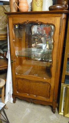 a wooden cabinet with a glass door in the middle of a room