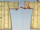 deux morceaux de tissu doré, ornés de rubans rouges, sont accrochés au mur