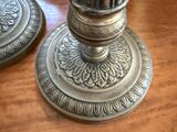 two silver candles on a wooden table next to a cell phone