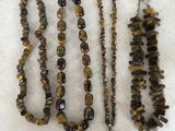 plusieurs colliers et bracelets composés de perles en œil-de-tigre, posés sur une table